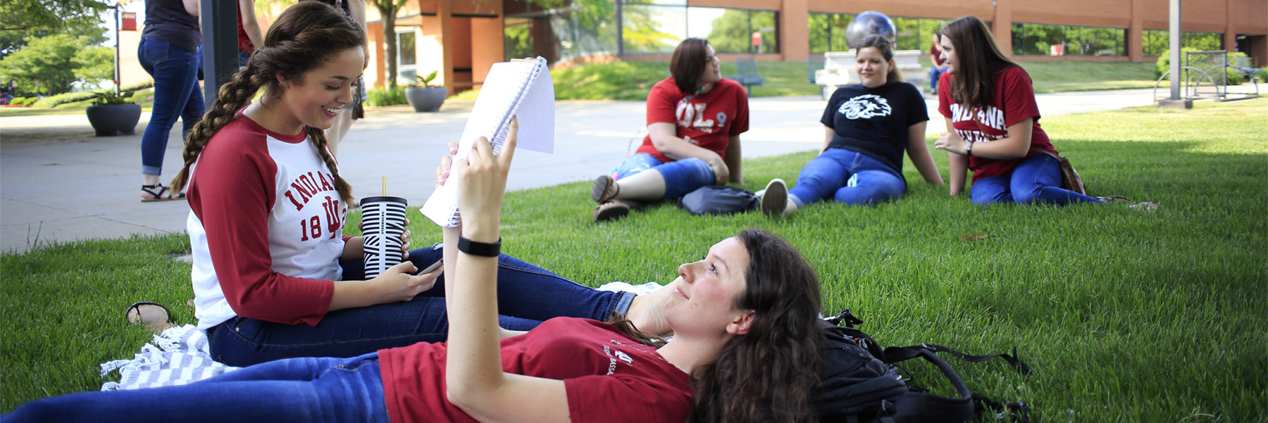 girls laying in the grass reading