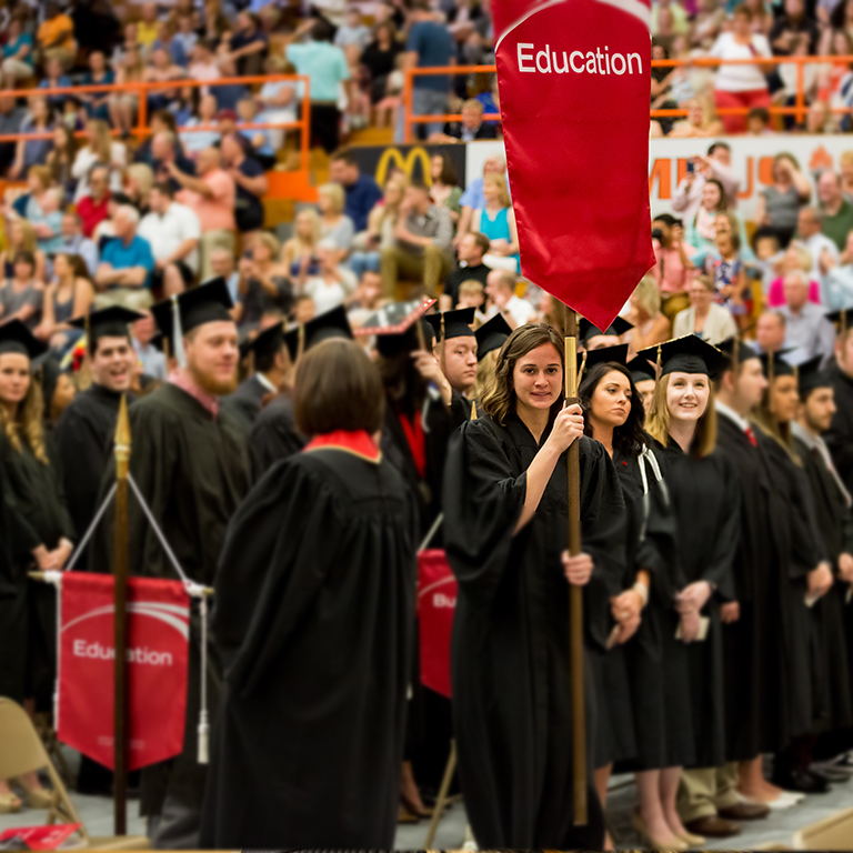 Image of a student holding education banner at commencement.